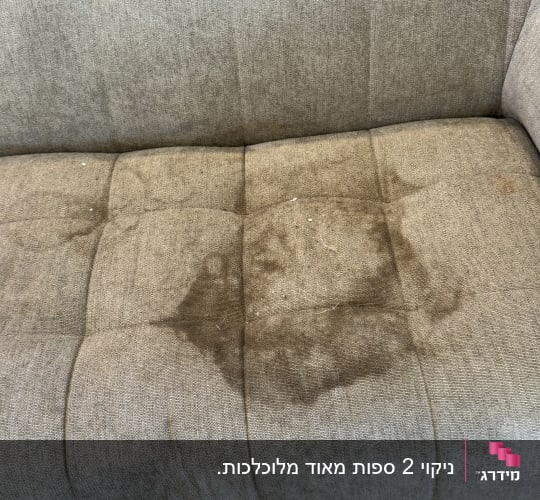כתם נוזל גדול על מושב ספת בד אפורה לפני ניקוי